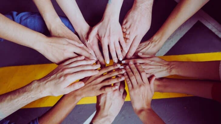 An overhead shot of a bunch of hands coming together to show the importance of community