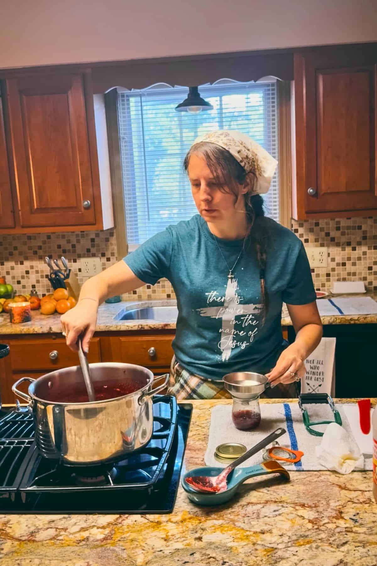 Elle making homemade Christmas jam in her kitchen, ladling hot jam into jars as part of the canning process.