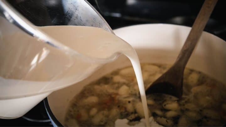 Pouring whole cream into gnocchi soup