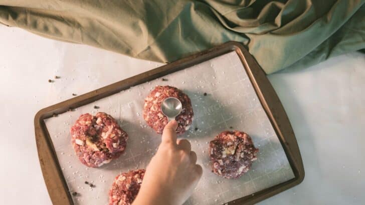 Using a tablespoon to create indents in venison burger patties to prevent shrinking during cooking.