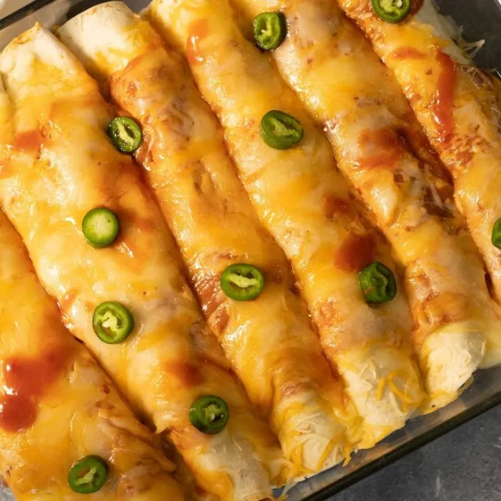 Venison enchiladas topped with melted cheese and fresh jalapeño peppers