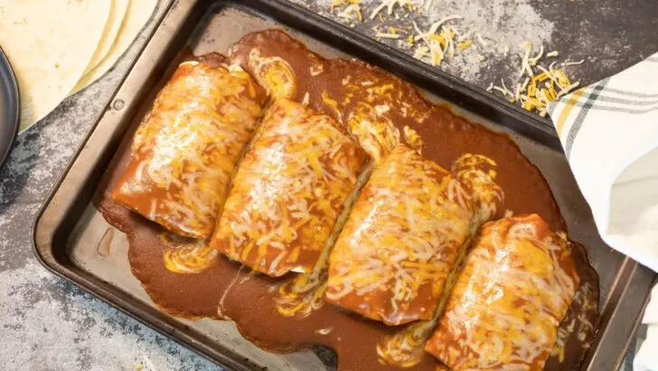 Sheet pan with smothered, wet burritos.