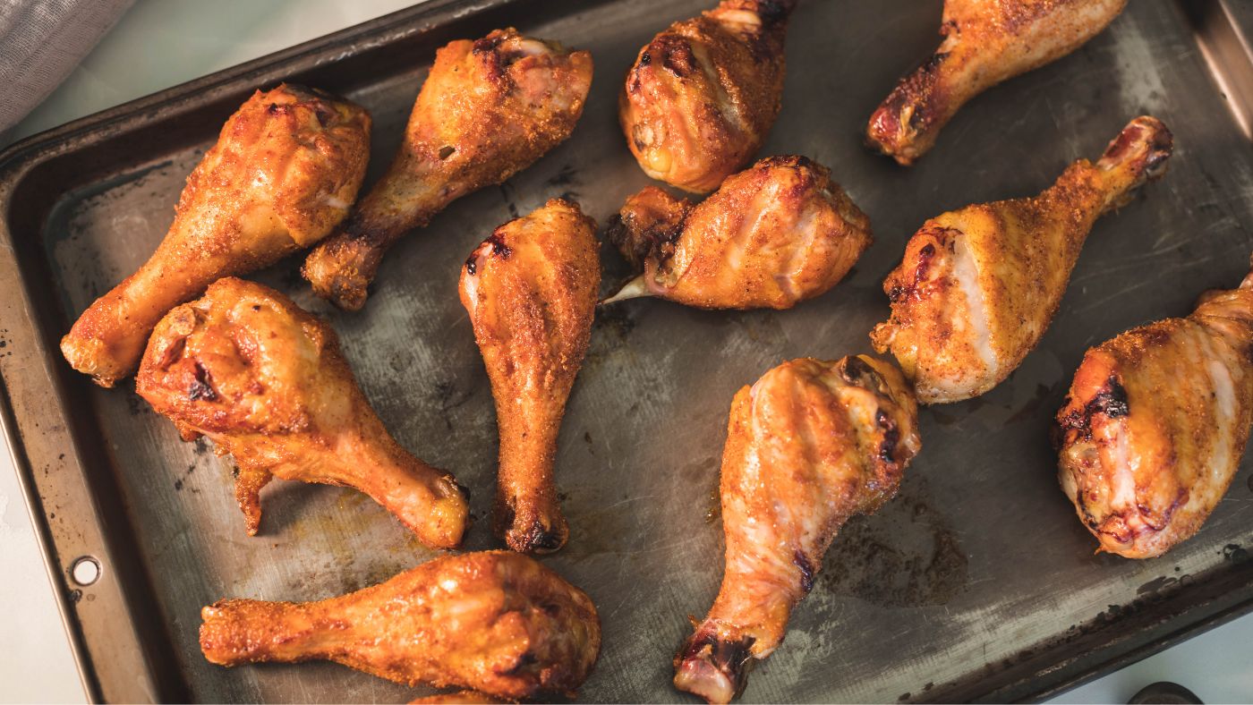 Smoked chicken drumsticks scattered on a sheet pan