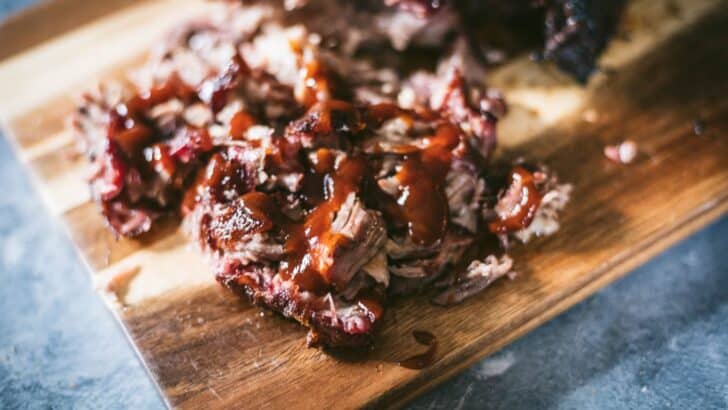 Pulled pork on a board coated with bbq sauce.