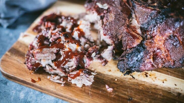 Smoked pork butt turned into pulled pork and covered in barbecue sauce sitting on a table.