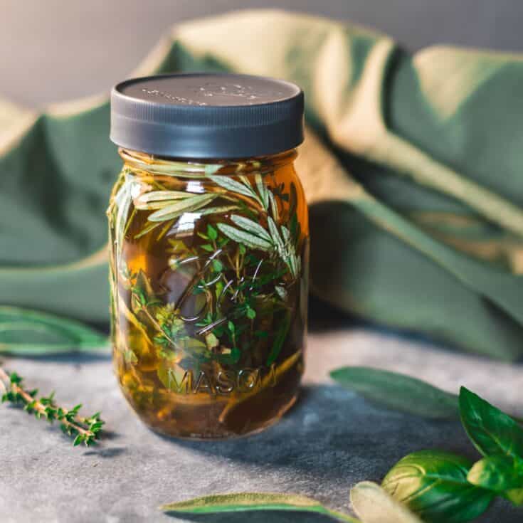 A jar of four thieves vinegar steeping with fresh herbs.