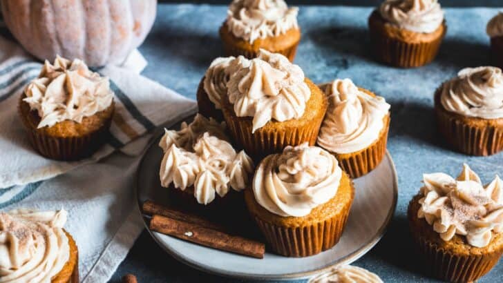 Several pumpkin spice cupcakes topped with icing sitting on a counter.