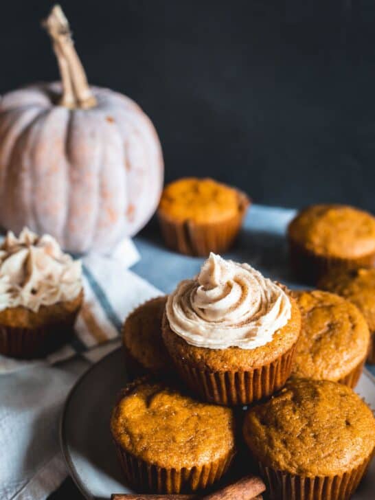 Pumpkin spice cupcakes stacked on a counter.