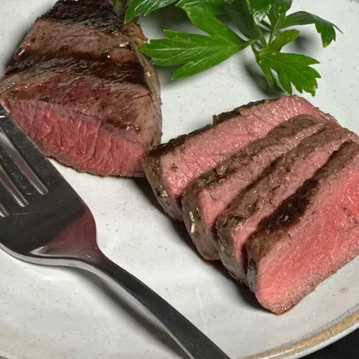 Venison steak cooked to rare sliced on a plate