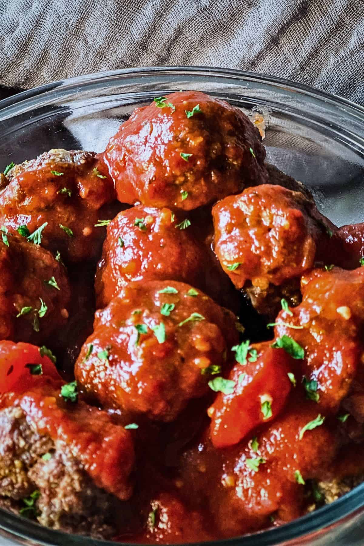 baked venison meatballs in tomato sauce cooling in a glass bowl before freezing for meal prep