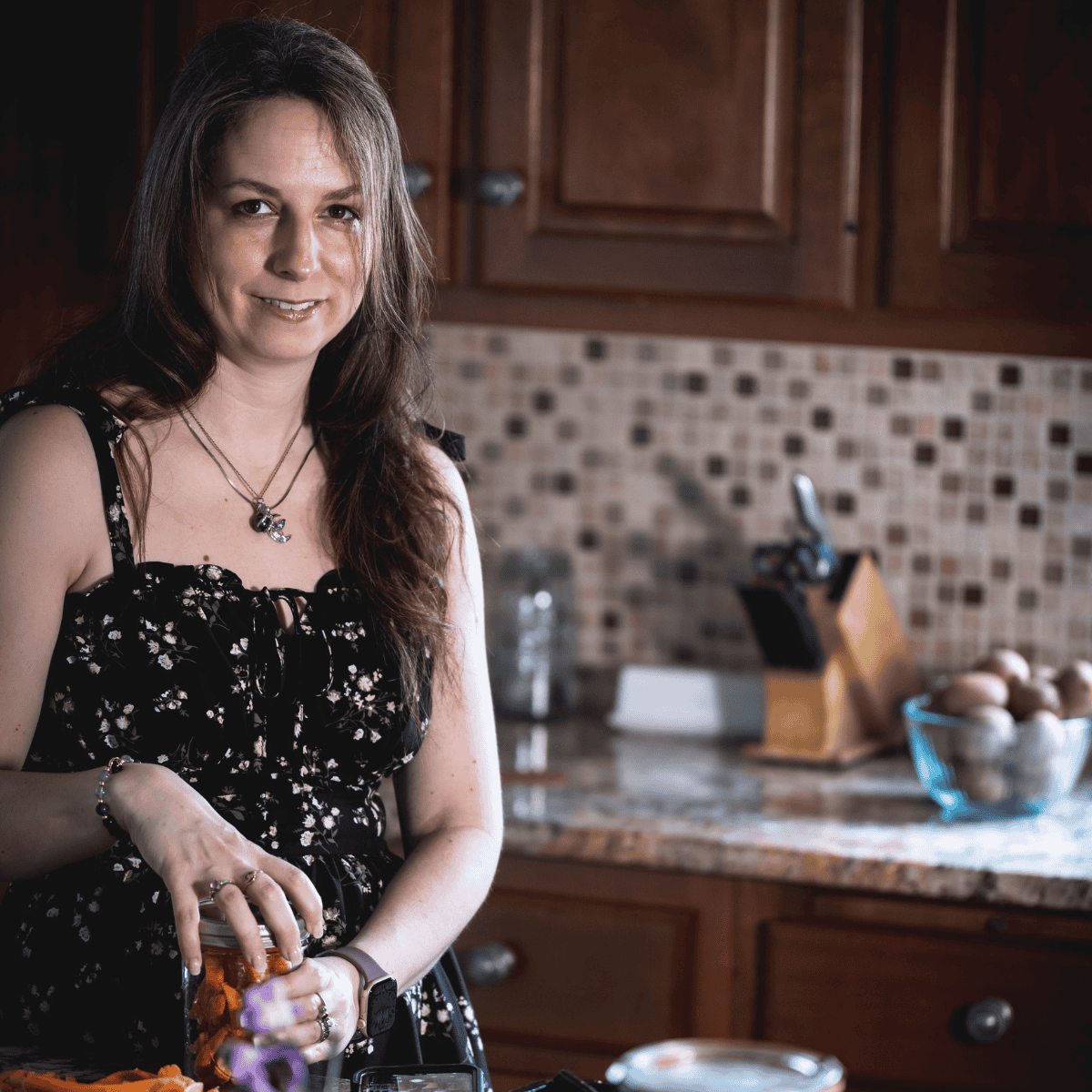 Elle in her kitchen preparing and preserving fresh carrots in a glass jar, representing seasonal cooking and food preservation