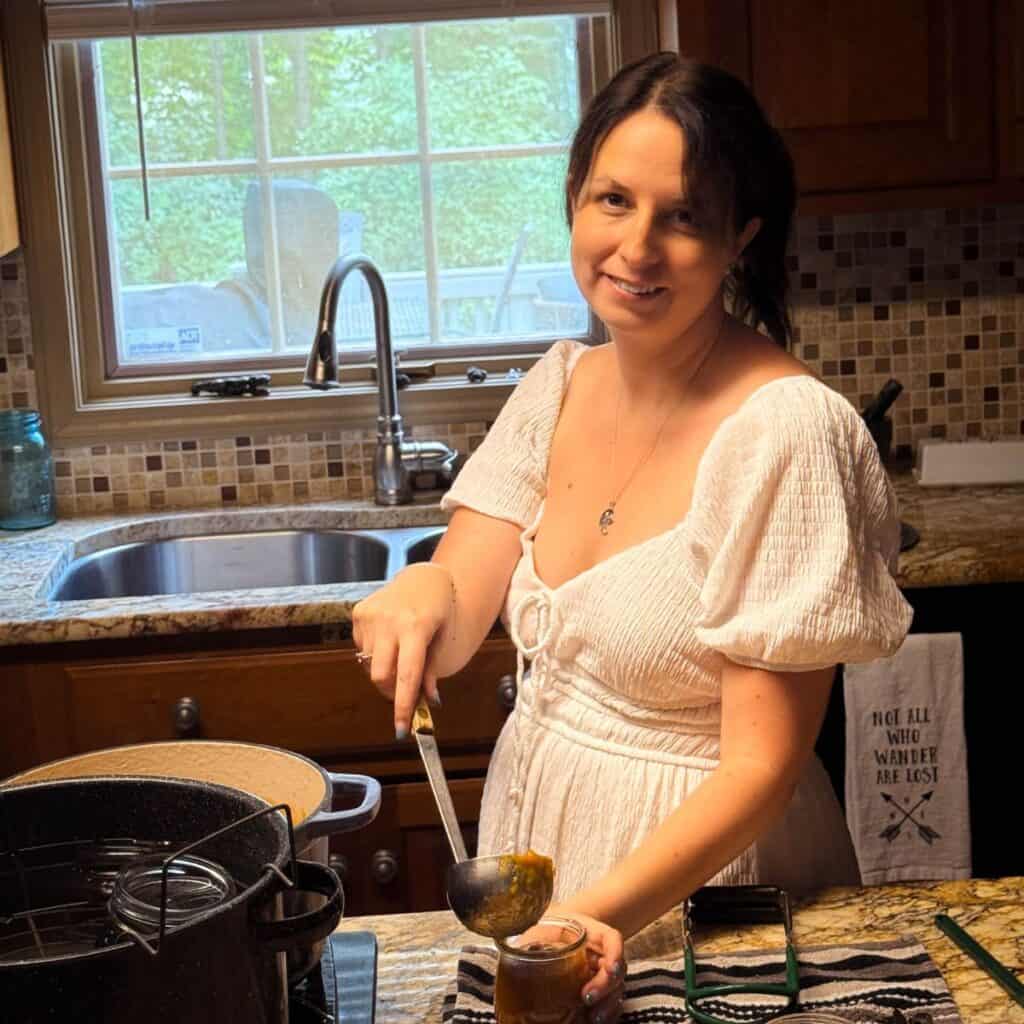 Persephone from The Rustic Elk canning homemade peach preserves in a real Midwest kitchen, showcasing hands-on food preservation skills and from-scratch cooking expertise.