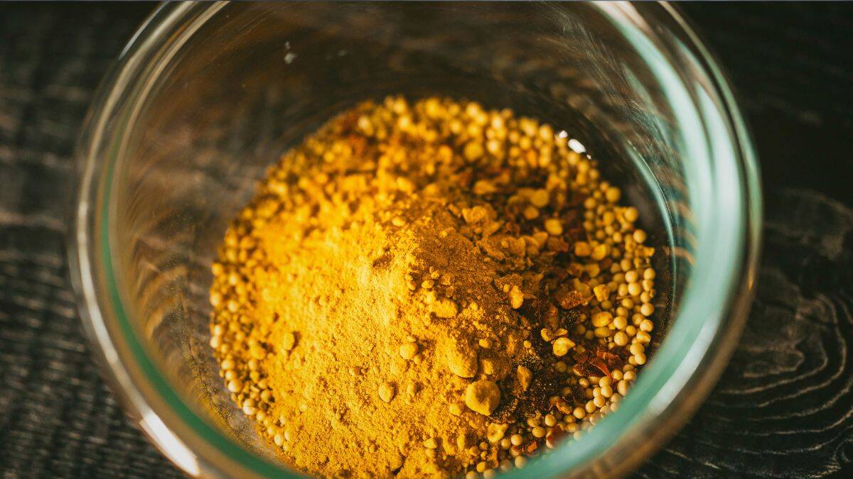 Canning spice blend with turmeric, mustard seed,celery seed, nutmeg, and crushed red pepper in a glass bowl