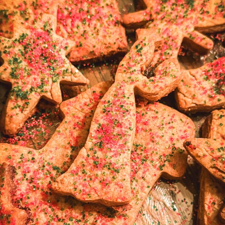 Freshly baked St. Nicholas speculaas cookies topped with red and green sugar on a festive platter.