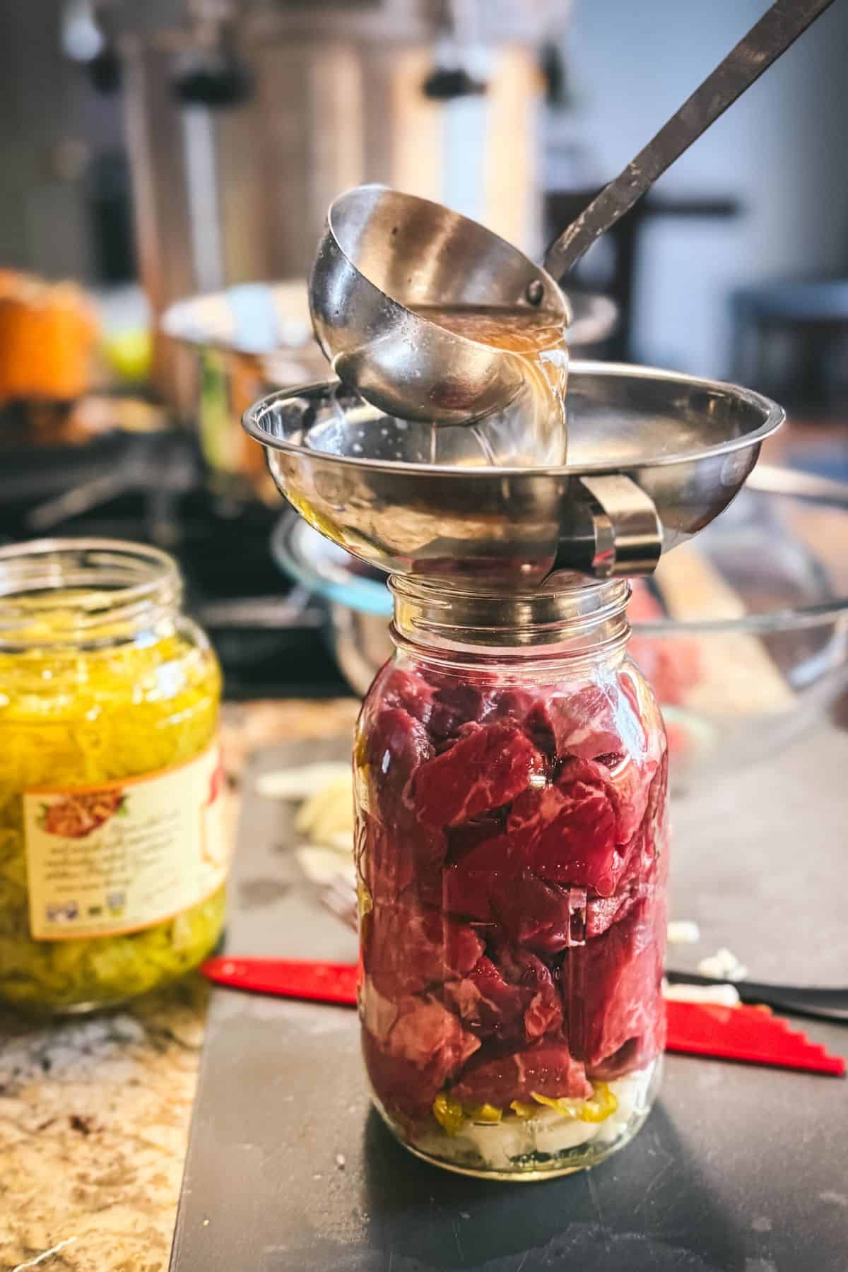 Adding seasoned liquid to a raw-packed quart jar of Mississippi pot roast before pressure canning