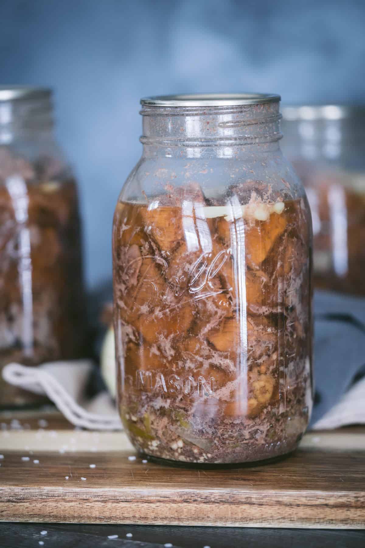 Quart jar of pressure-canned Mississippi pot roast with tender beef, broth, and pepperoncini peppers