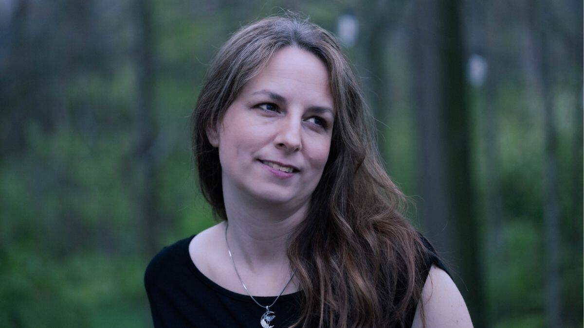 Elle, creator of The Rustic Elk, standing in a forest with a soft, natural expression