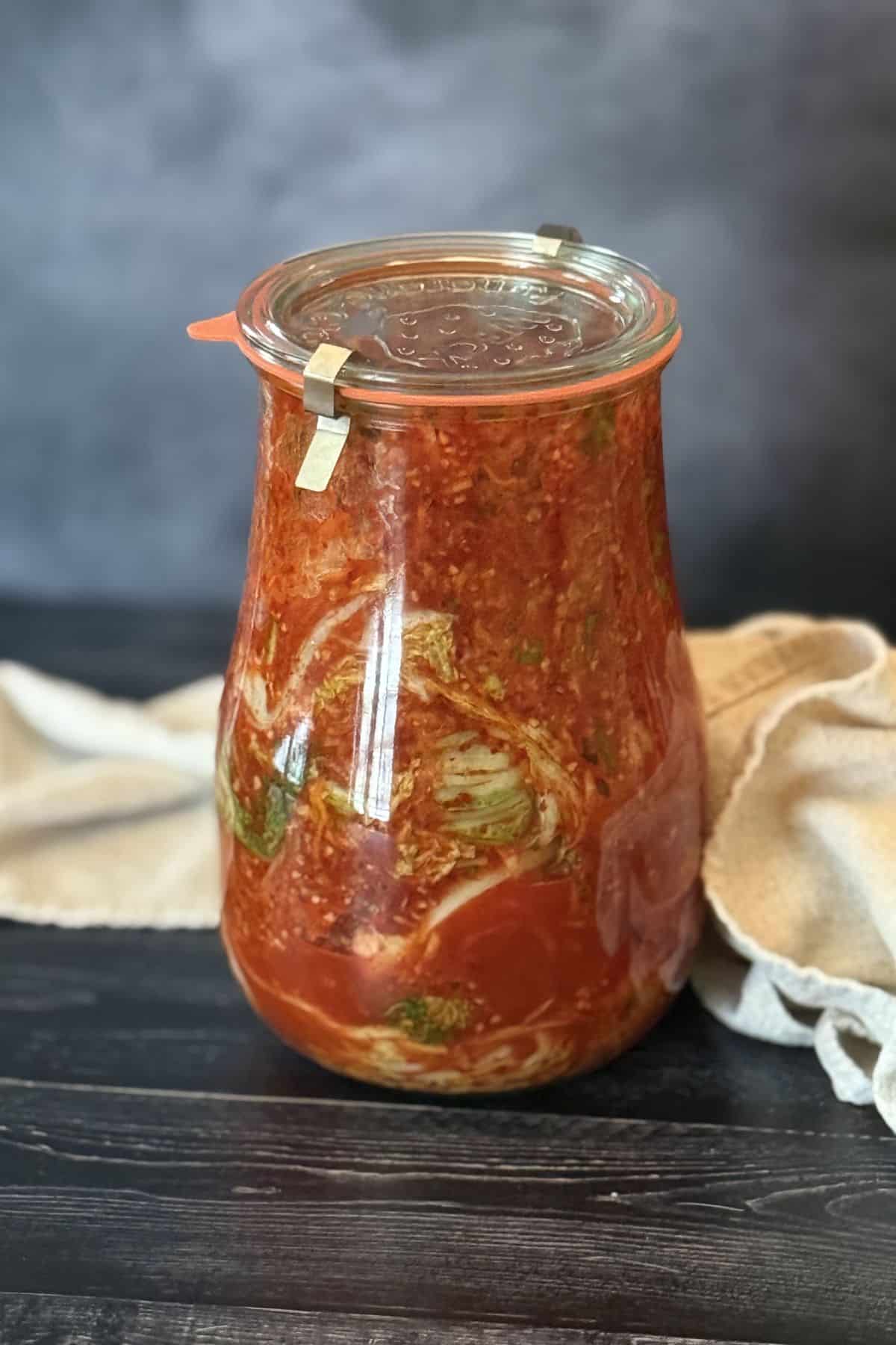 Homemade napa cabbage kimchi in a jar, fermenting with chili flakes, garlic, and vegetables