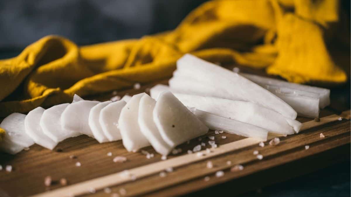 sliced daikon radish on wooden board with salt, ready for pickling