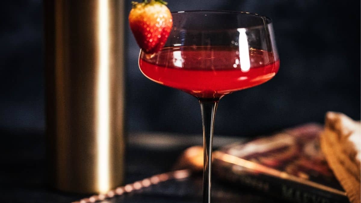 Fresh strawberry lemon drop martini with homemade strawberry syrup served in a coupe glass and garnished with a ripe strawberry.