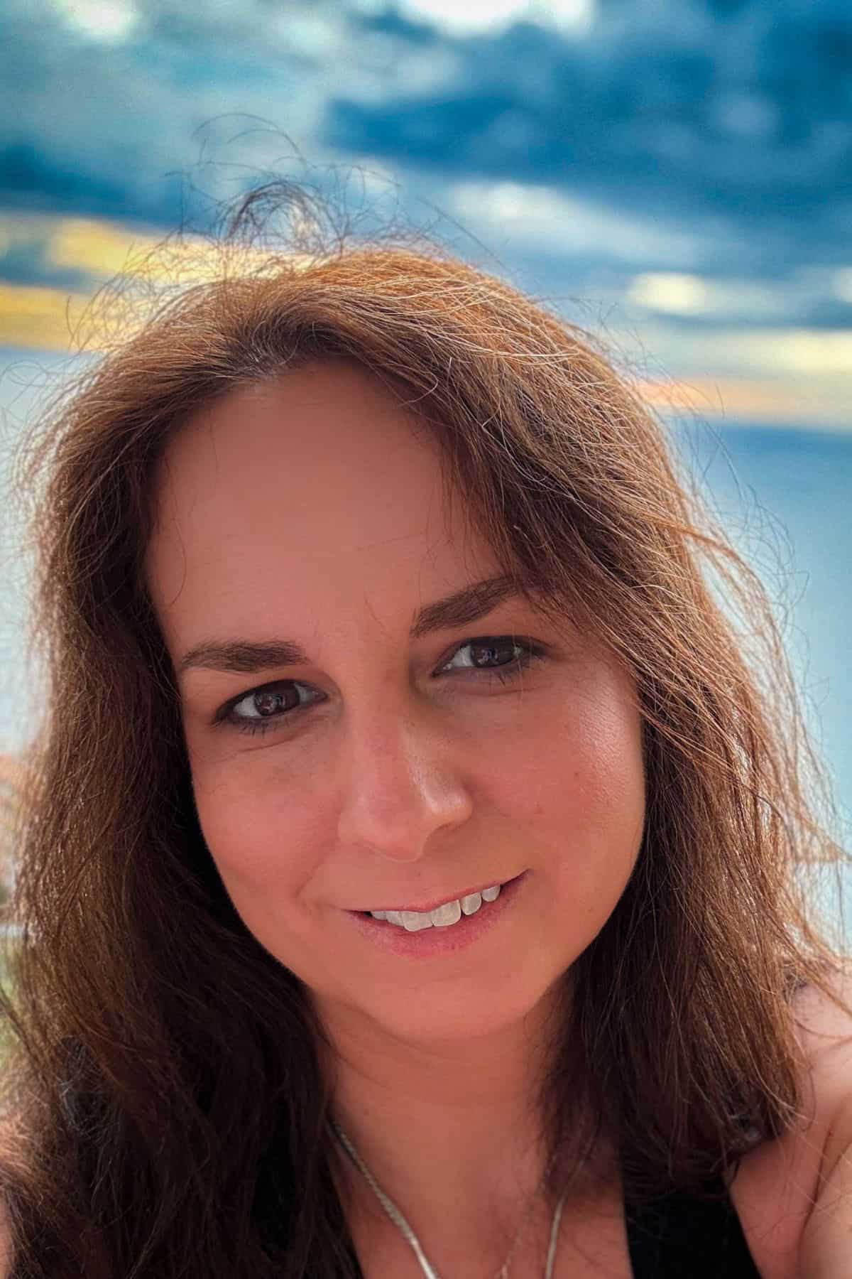 Portrait of Elle smiling with the ocean and dramatic clouds in the background during a trip to Puerto Vallarta.