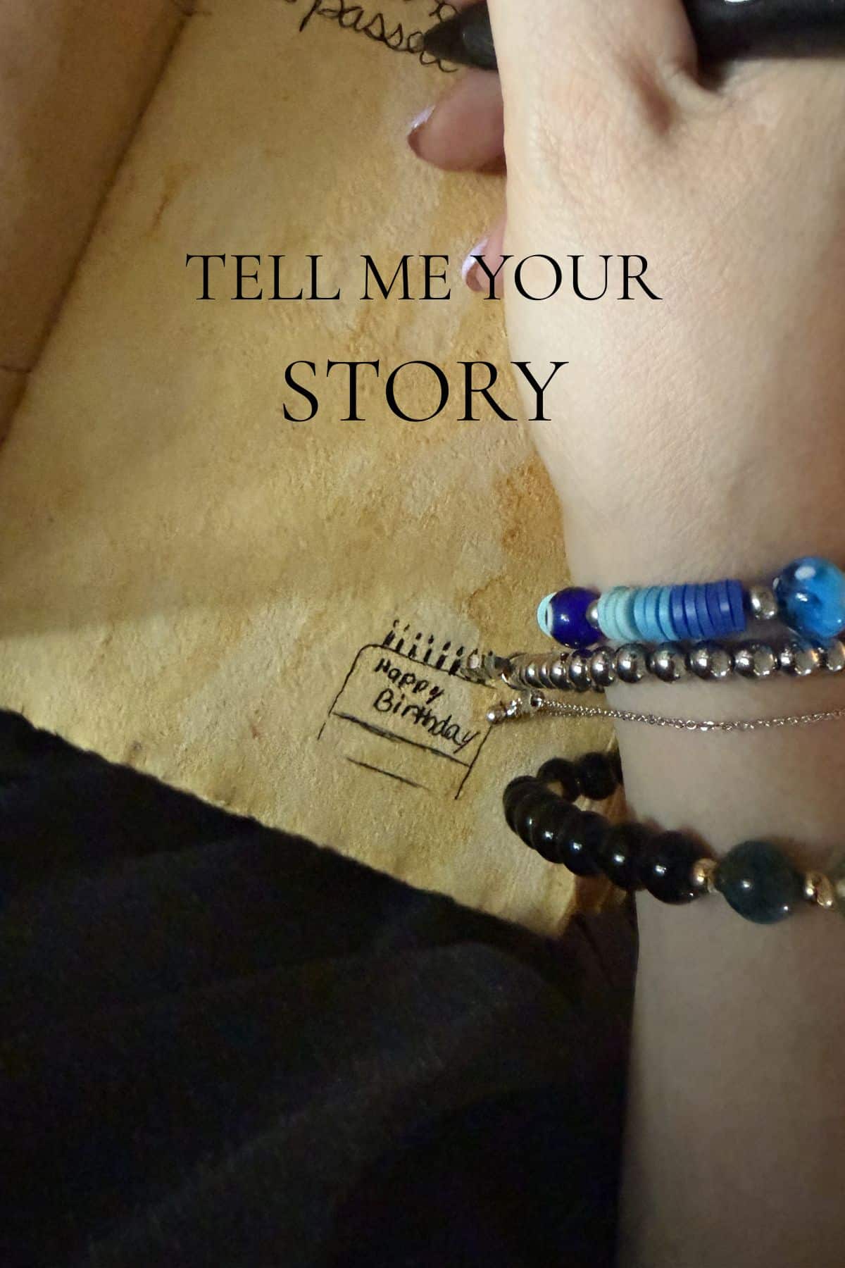 Hand writing a message in a wooden guestbook with "Tell Me Your Story" overlaid, inviting visitors to get in touch.