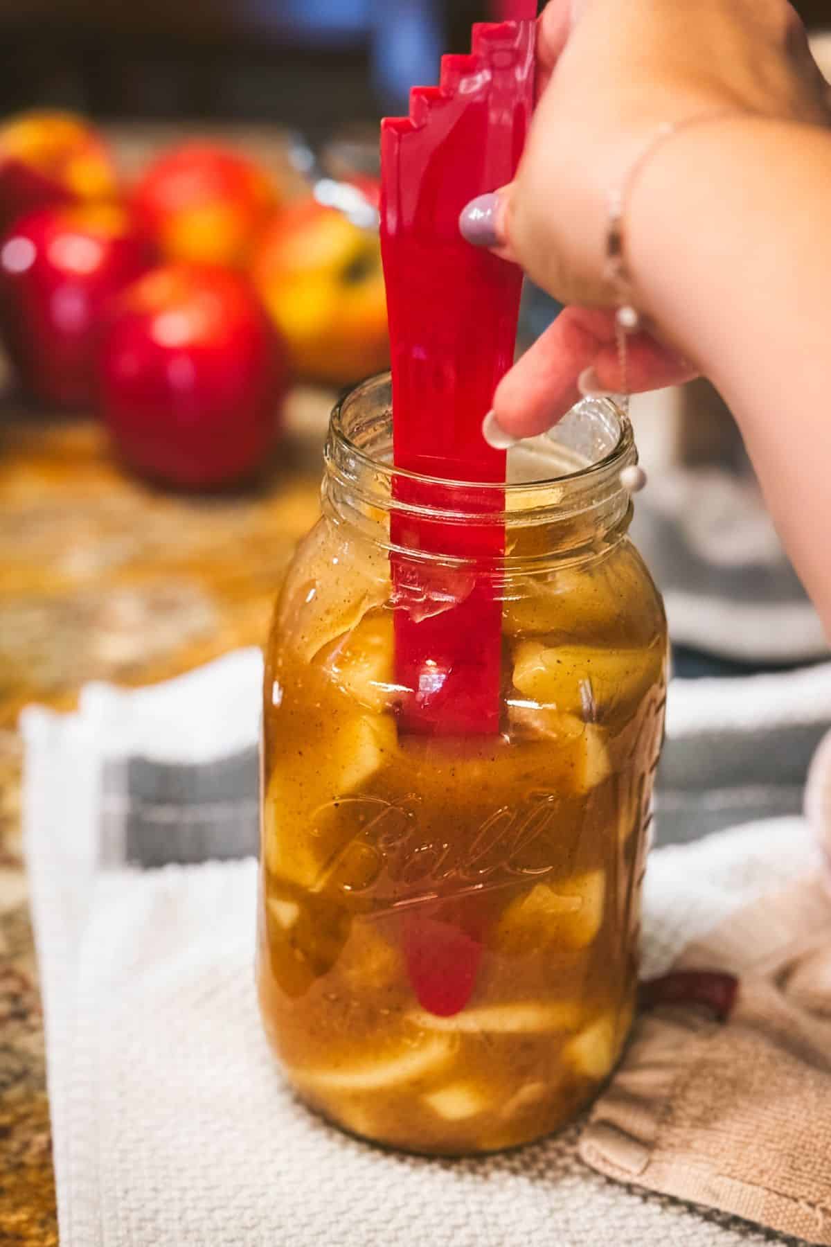 Using a bubble remover and headspace tool to prepare a mason jar for water bath canning.