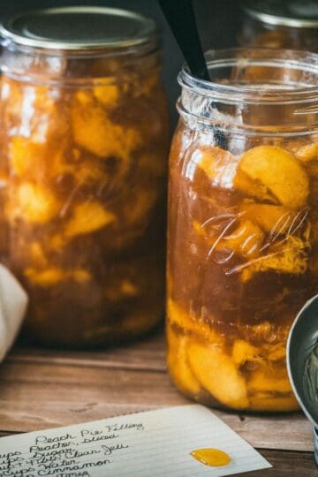 Homemade canned peach pie filling in Ball mason jars made with fresh peaches, Clear Jel, cinnamon, and vanilla using a safe water bath canning recipe.